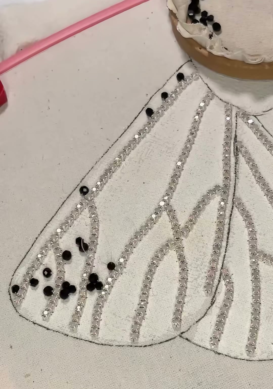 Step 04 — Black faceted beads placed along the lower edges of the wings, beginning the signature spotted pattern