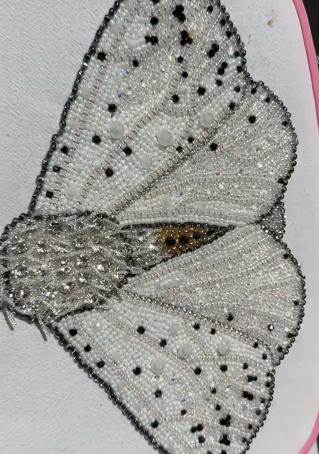 Step 18 — The completed moth bag laid flat, showing the full wingspan, beaded handle, and the contrast between silver wings and dark edges