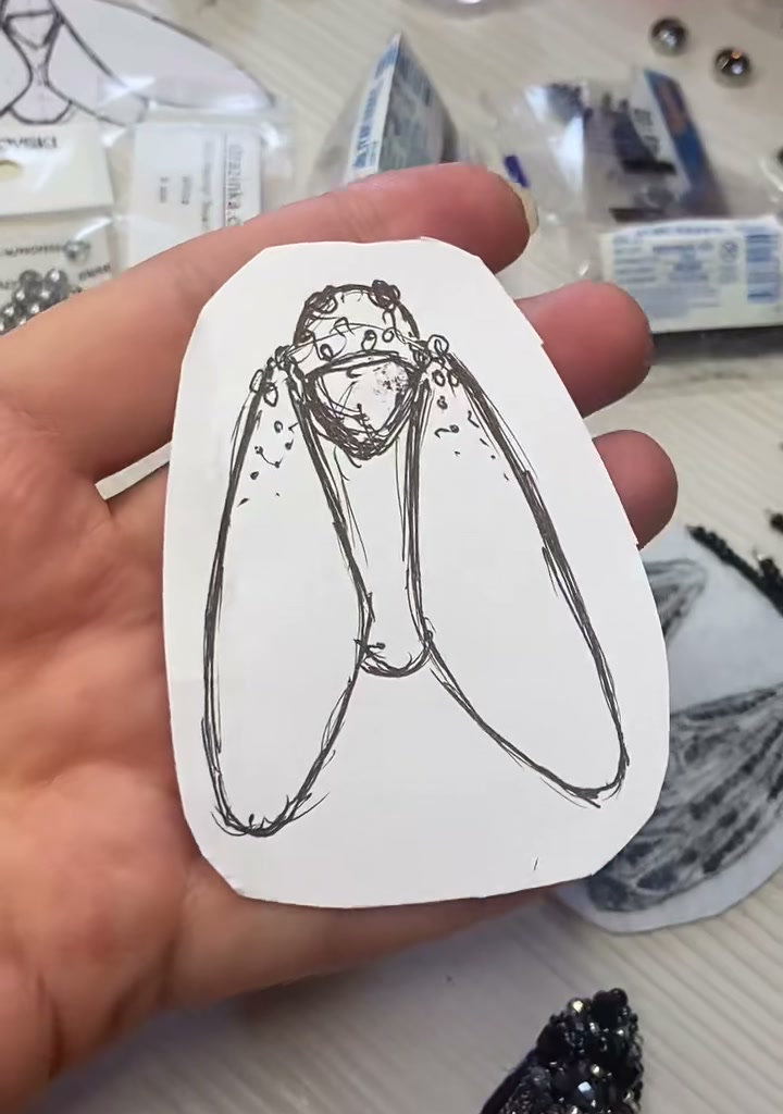 Step 03 — A black felt cicada body with a large faceted black rhinestone placed at the thorax, surrounded by smaller black seed beads