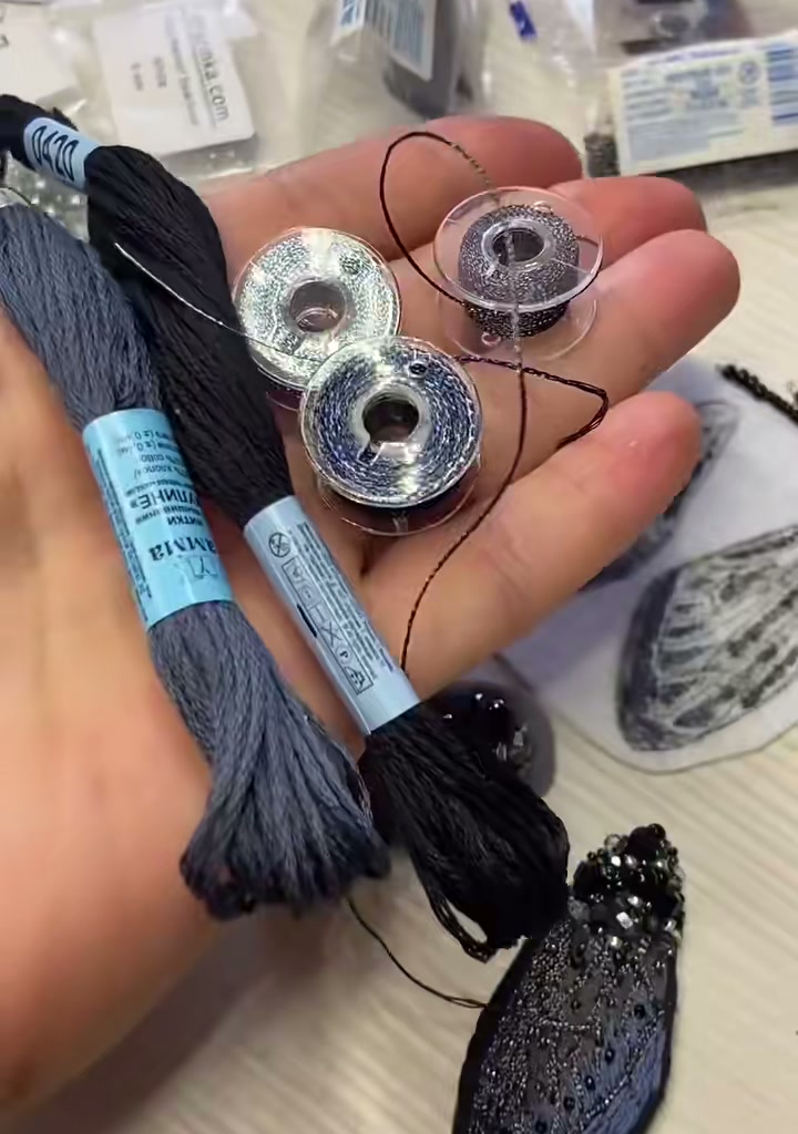Step 02 — Skeins of embroidery floss in black and midnight-blue, alongside two silver metallic thread bobbins