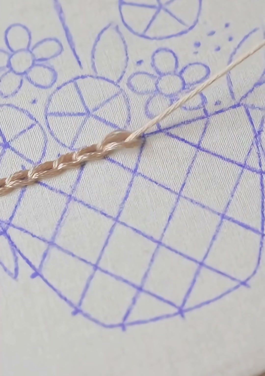 Step 01 — A water-soluble marker outline of the basket, flowers, and leaves, with the first row of tan satin stitches worked across the basket body