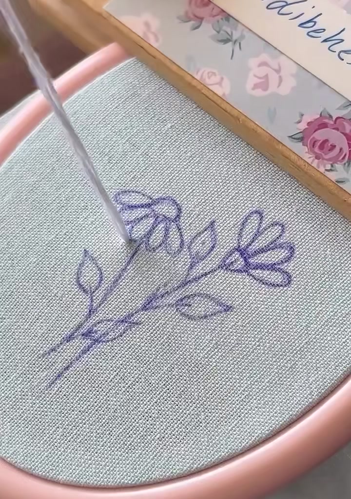 Needle coming up through the fabric at the center of the first drawn daisy