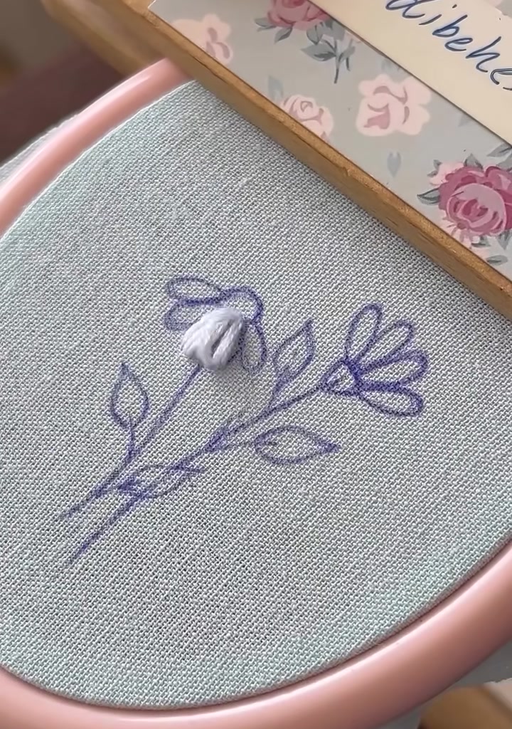 Needle adding another satin stitch petal to the first daisy
