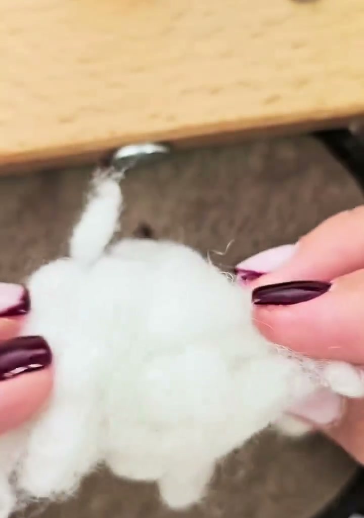 Step 07 — A small tuft of white polyester stuffing held between fingers