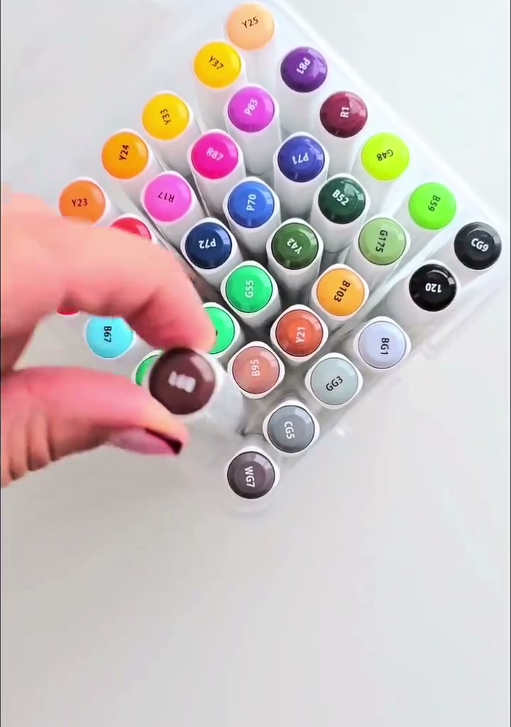Step 10 — A hand selecting a dark brown alcohol marker from a colorful marker set