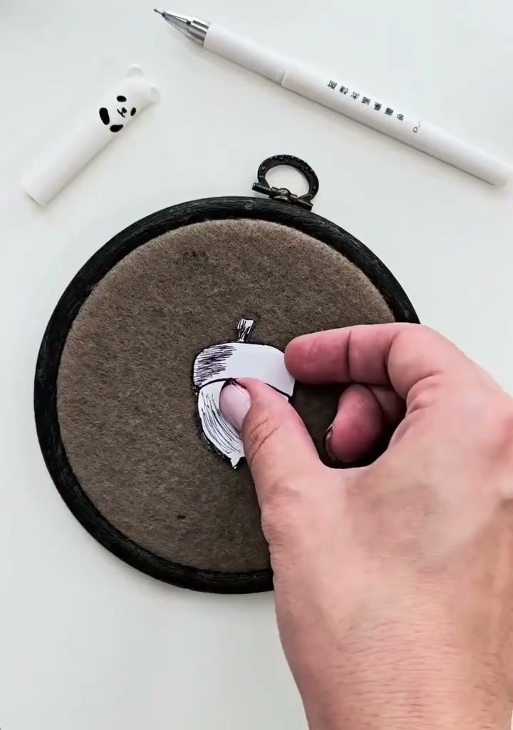 Step 04 — The opened paper acorn template held above the hoop