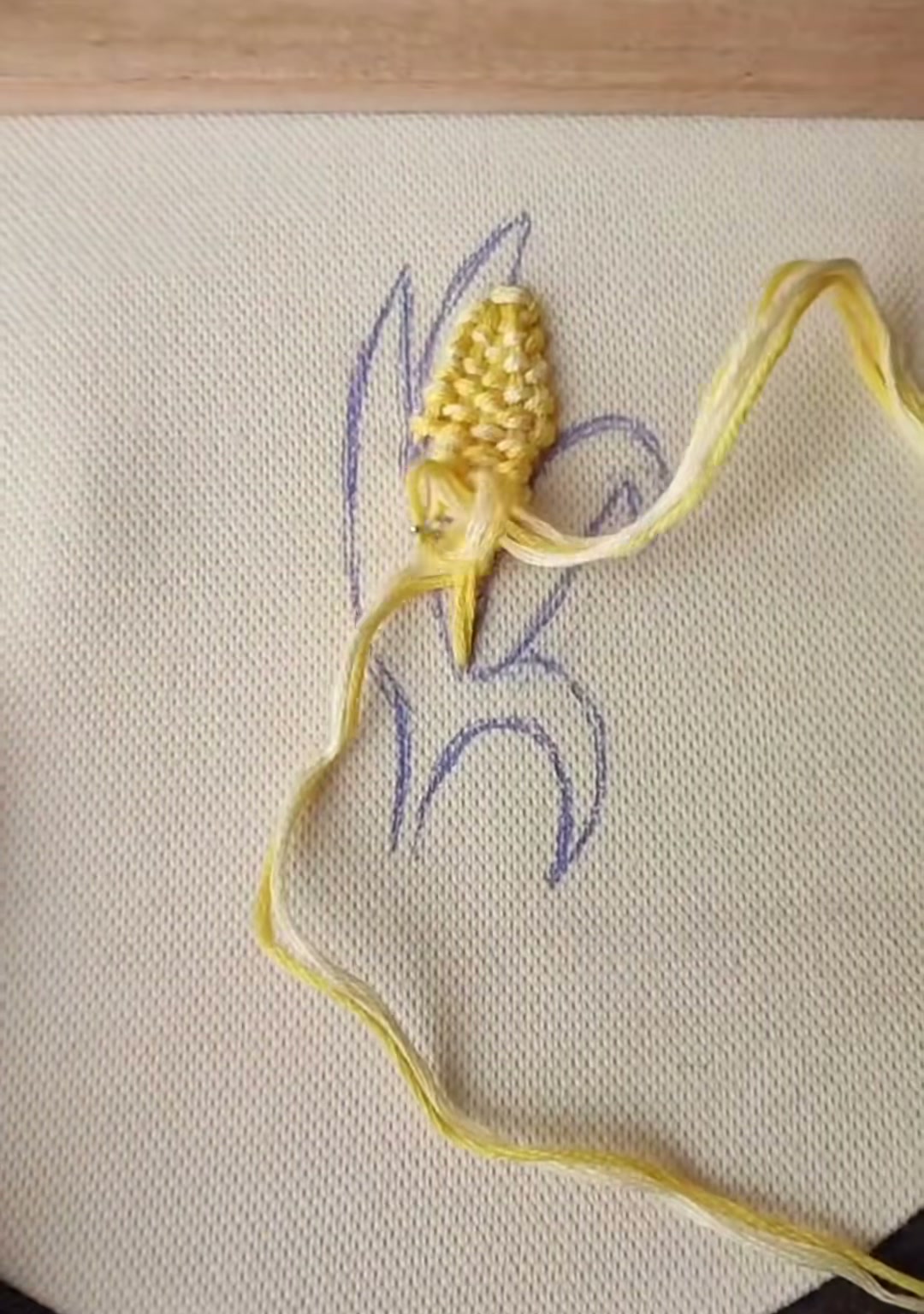 Step 7 — The first dark green husk leaf stitched along the left side of the corn ear with satin stitch