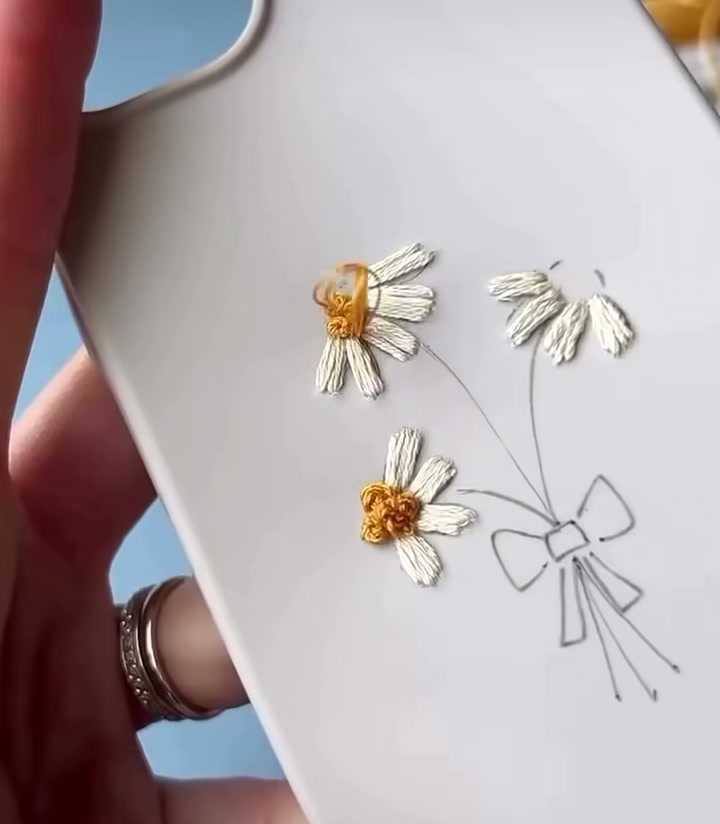 Step 05 — Two finished daisies with clean white petals and golden centers