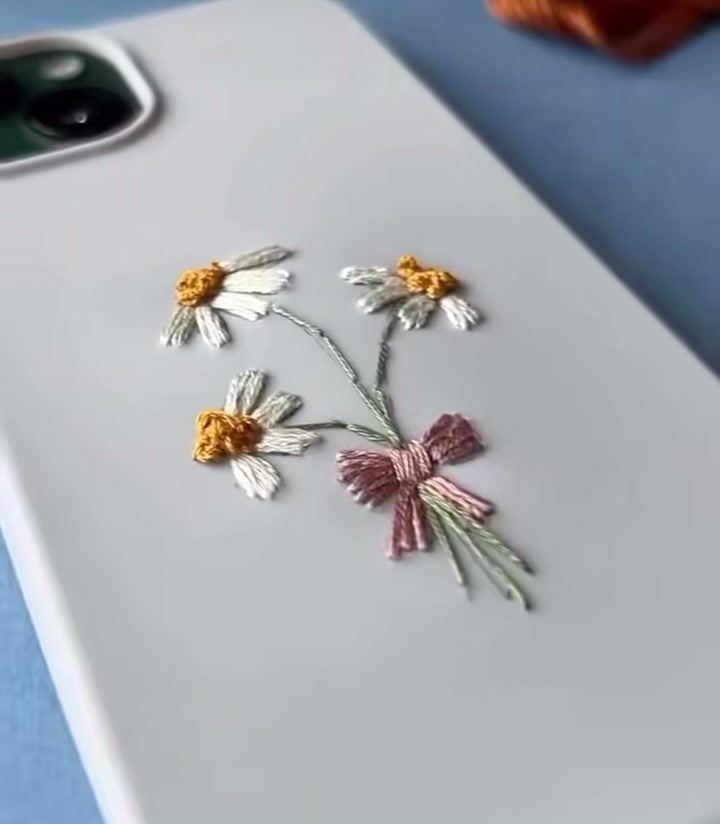 Step 12 — A close-up of the embroidered daisies and bow