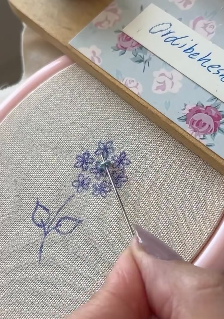 Needle forming the first straight stitch of a star-shaped flower