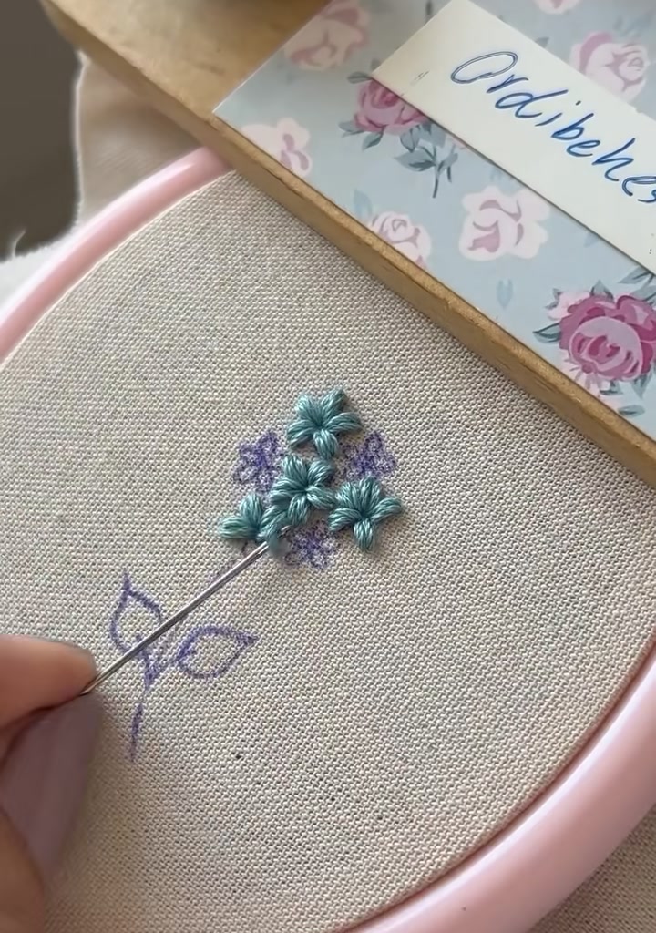 Needle beginning to form a small bud with light blue stitches